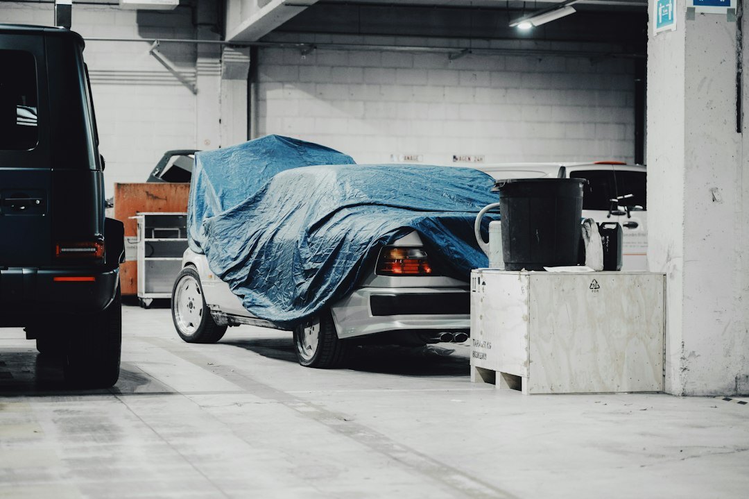 Dust covers partially removed from classic cars in a hidden garage